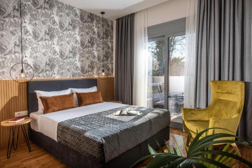 sypialnia z łóżkiem i żółtym krzesłem w obiekcie Kipos Boutique Suites w Heraklionie