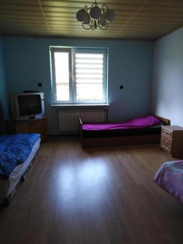 Habitación con 2 camas, TV y ventana. en noclegi kwatery, en Wola Rębkowska