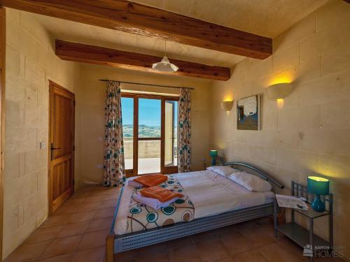 um quarto com uma cama e uma grande janela em The Blue House Holiday Home em Għasri