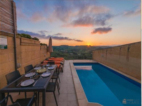 a patio with a table and a swimming pool at The Blue House Holiday Home in Xagħra