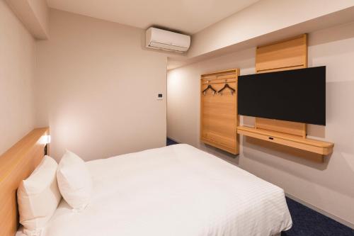 a hotel room with a bed and a flat screen tv at Sotetsu Grand Fresa Kumamoto in Kumamoto