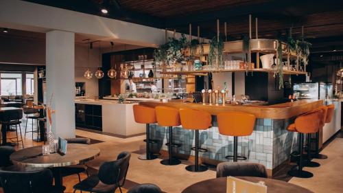 a bar in a restaurant with orange chairs and tables at Moeke Mooren in Appeltern