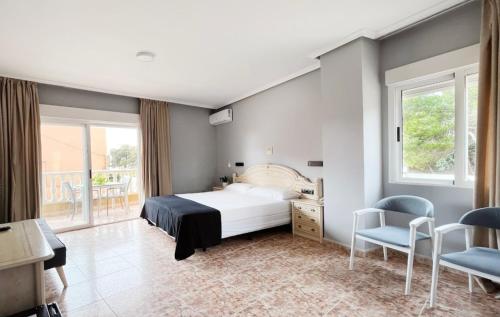1 dormitorio con 1 cama, escritorio y sillas en Hotel ParqueMar Premium Beach, en Guardamar del Segura