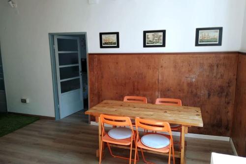 ジェノヴァにあるBilocale nel cuore di Genovaの木製テーブル(周囲にオレンジの椅子3脚付)