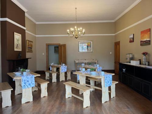 a dining room with tables and benches and a chandelier at Lindela House in Kokstad