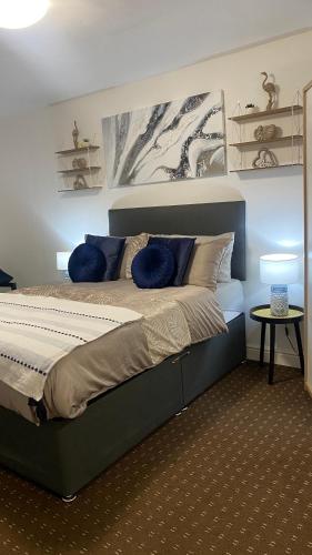 1 dormitorio con 1 cama grande con almohadas azules en Bv Homely Studio Fourteen At Deighton Huddersfield, en Huddersfield