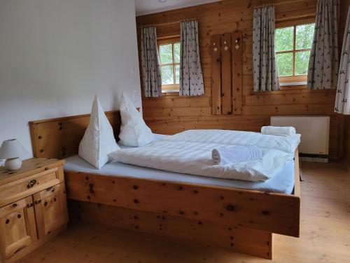 Schlafzimmer mit einem Holzbett mit weißer Bettwäsche und Kissen in der Unterkunft Appartement Günther in Schladming