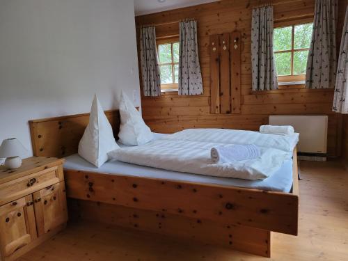 - une chambre dotée d'un lit en bois avec des draps et des oreillers blancs dans l'établissement Appartement Günther, à Schladming