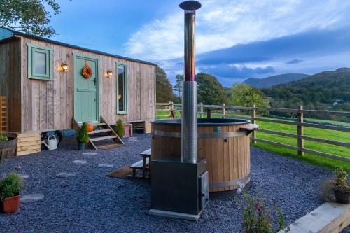 a small cabin with a wood stove in a yard at Elephant View Shepherds Hut in Caernarfon