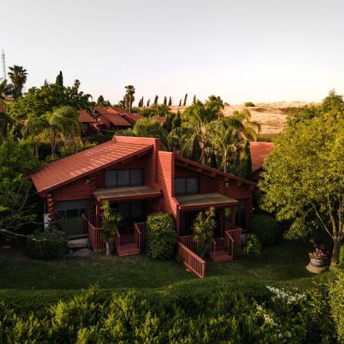 a house with a red roof and some trees at Ein Harod Country Lodge in ‘En H̱arod