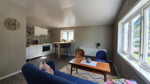 Kaikanten Kro og Rorbu في Sennesvik: غرفة معيشة مع أريكة زرقاء وطاولة
