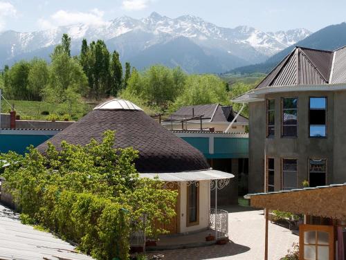a building with a roof with mountains in the background at Barskoon Guest House in Barskoon