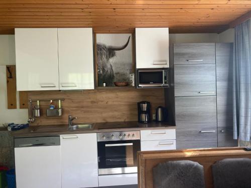 uma cozinha com armários brancos e uma vaca na parede em Apartment Eisenhut - EBE500 by Interhome em Hüttau