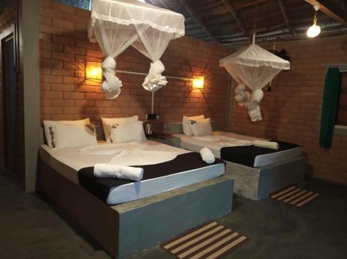two beds in a room with a brick wall at Sandalwood Cottage in Udawalawe
