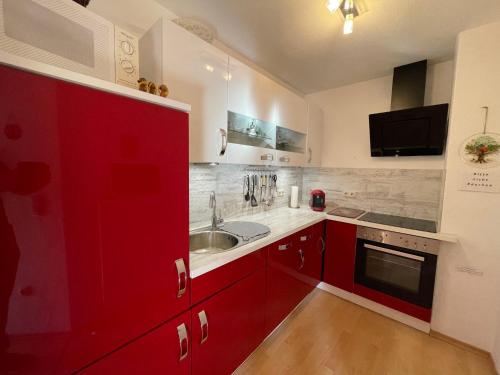 a kitchen with red cabinets and a sink at Apartment Kühbeck-1 by Interhome in Bischofsmais