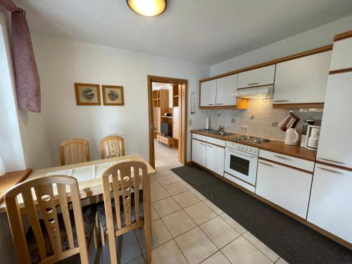 a kitchen with white cabinets and a table and chairs at Apartment Janik by Interhome in Bischofsmais