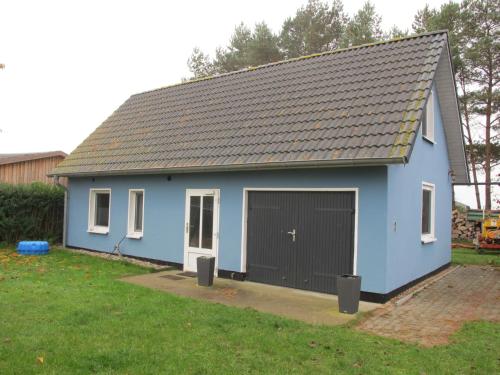 a blue house with a garage in a yard at Holiday Home Ostwind by Interhome in Ummanz