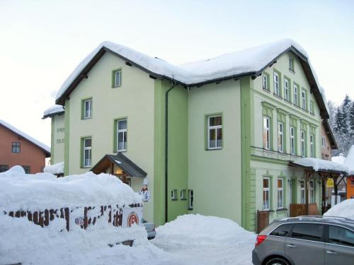 un edificio verde con nieve encima en Apartment Base Camp 2 by Interhome en Desná