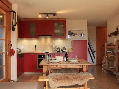 eine Küche mit roten Schränken und einem Holztisch in der Unterkunft Apartment Armorial II - apt 2 by Interhome in Villars-sur-Ollon