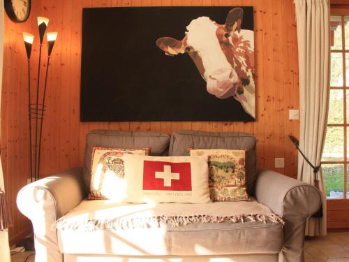 a couch in a room with a picture of a cow at Apartment Armorial II - apt 2 by Interhome in Villars-sur-Ollon