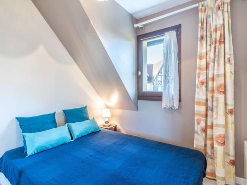 une chambre avec un lit bleu et une fenêtre dans l'établissement Apartment Fleur Marine-16 by Interhome, à Cabourg
