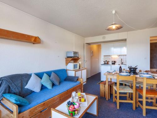 un salon avec un canapé bleu et une cuisine dans l'établissement Apartment Pegase Phenix-10 by Interhome, au Corbier