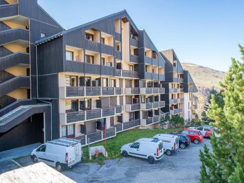 un immeuble d'appartements avec des voitures garées dans un parking dans l'établissement Apartment Le Sarvan-9 by Interhome, aux Menuires