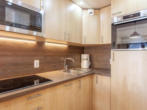 La cuisine est équipée de placards en bois, d'un évier et d'un four micro-ondes. dans l'établissement Apartment Les Tommeuses - Val Claret-2 by Interhome, à Tignes