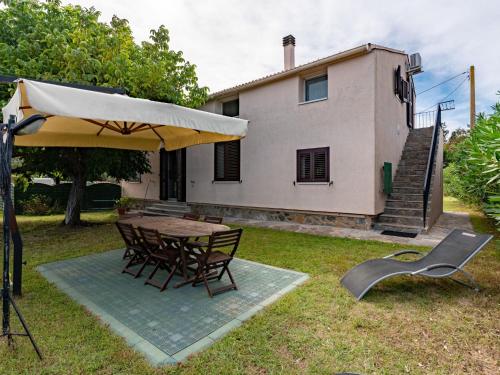 un patio avec une table, des chaises et un parasol dans l'établissement Apartment Villa Volpajola by Interhome, à Cervione
