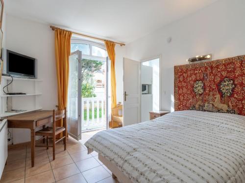 Dormitorio con cama, escritorio y TV en Apartment Le Chalet by Interhome, en Cabourg