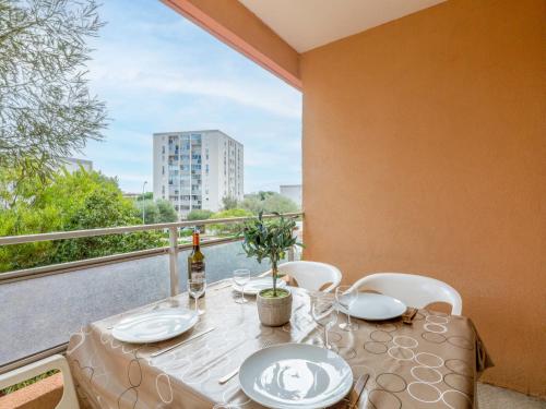 a table with white plates and chairs on a balcony at Apartment Les Pins Ensoleilles-7 by Interhome in Sainte-Maxime