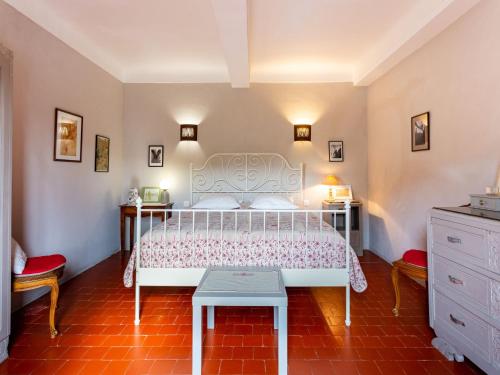 a bedroom with a white bed and a red tile floor at Holiday Home L'Olivier by Interhome in Ménerbes