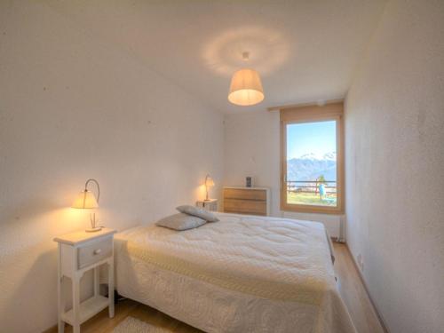 een witte slaapkamer met een bed en een raam bij Apartment Topaze-2 by Interhome in Anzère