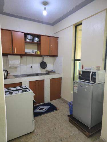 a small kitchen with a stove and a microwave at Urban Apartment in Naivasha