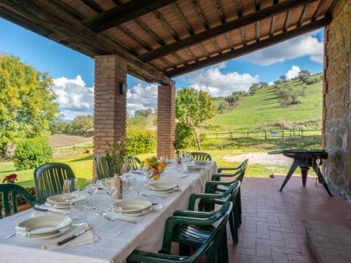 uma mesa longa com cadeiras e pratos num pátio em Holiday Home Poggio Campana by Interhome em Montemerano