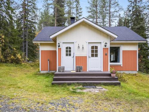 ein kleines weißes und orangefarbenes Haus mit einer Veranda in der Unterkunft Holiday Home Saapunkijärvi- pitkäperä by Interhome in Saapunki