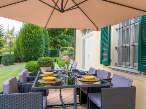 uma mesa e cadeiras com um guarda-sol num pátio em Holiday Home Villa Carlotta by Interhome em Costigliole dʼAsti