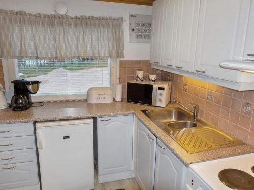 een keuken met witte kasten, een spoelbak en een magnetron bij Holiday Home Järvelä by Interhome in Kemijärvi