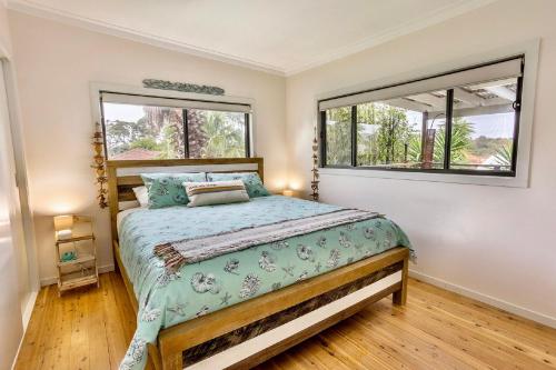 a bedroom with a bed and two windows at Sunset Haven in Shoalhaven Heads