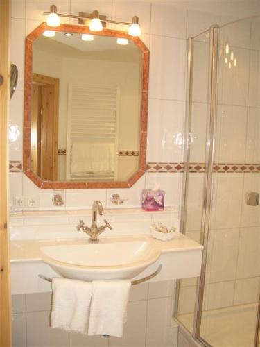 a bathroom with a sink and a shower with a mirror at Gasthof & Hotel Jägerwirt in Aufhofen