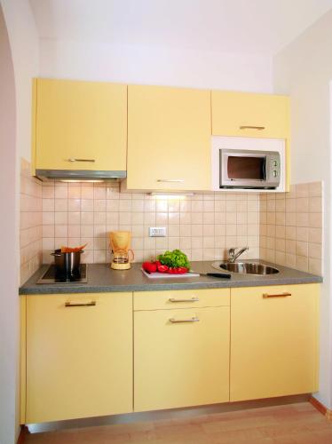 a kitchen with yellow cabinets and a sink at Hotel Haselried in Tirolo