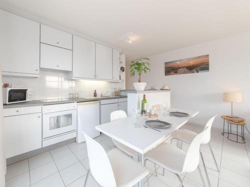 eine Küche mit weißen Schränken sowie einem weißen Tisch und Stühlen in der Unterkunft Apartment Wilde Zee by Interhome in Bredene-aan-Zee