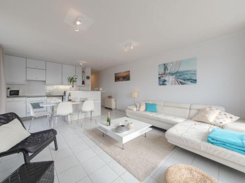 a white living room with a couch and a table at Apartment Wilde Zee with terrace by Interhome in Bredene-aan-Zee