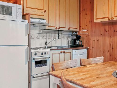 a kitchen with a white refrigerator and a table at Holiday Home Ylläskarpalo 3 päätyhuoneisto by Interhome in Äkäslompolo