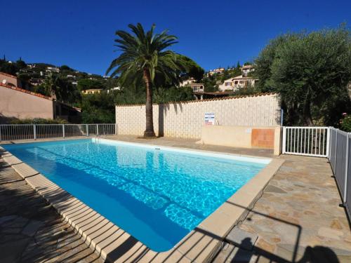 une piscine avec un palmier et une clôture blanche dans l'établissement Holiday Home Le Clos du Rigaud-3 by Interhome, à Cavalaire-sur-Mer