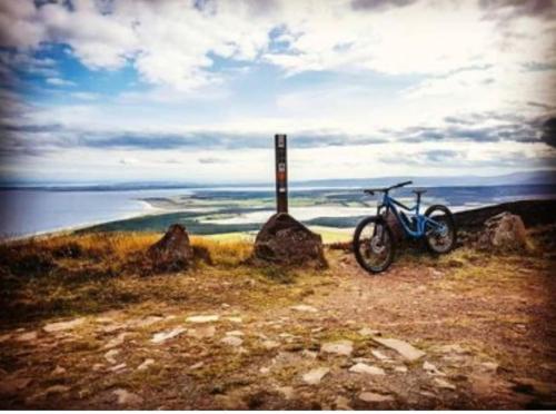 a bike parked next to a sign on a hill at Frasers Apartment in Golspie