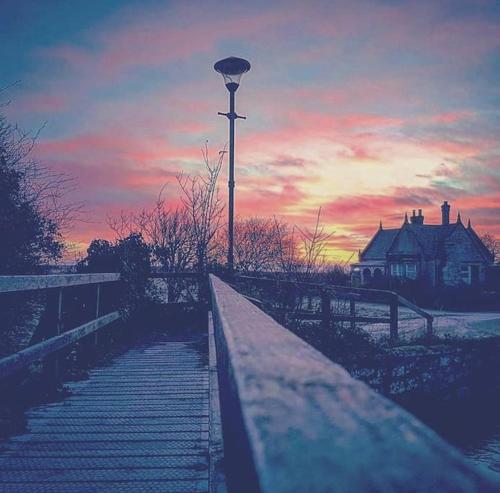 a pathway leading to a light pole with a sunset in the background at Frasers Apartment in Golspie