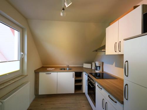 a small kitchen with white cabinets and a window at Apartment Müritz Ferienpark Röbel-8 by Interhome in Röbel