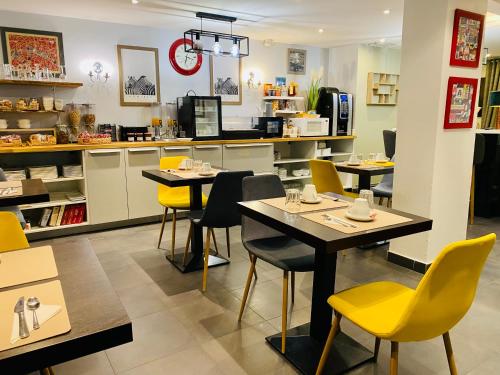 a restaurant with two tables and yellow chairs at Hôtel Clairefontaine in Paris