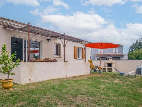 una casa con una sombrilla roja en el patio en Holiday Home A la porte d'Avignon by Interhome, en Laudun